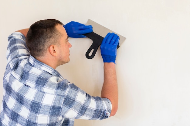 Kostenloses Foto mann, der eine kelle beim arbeiten an wand hält