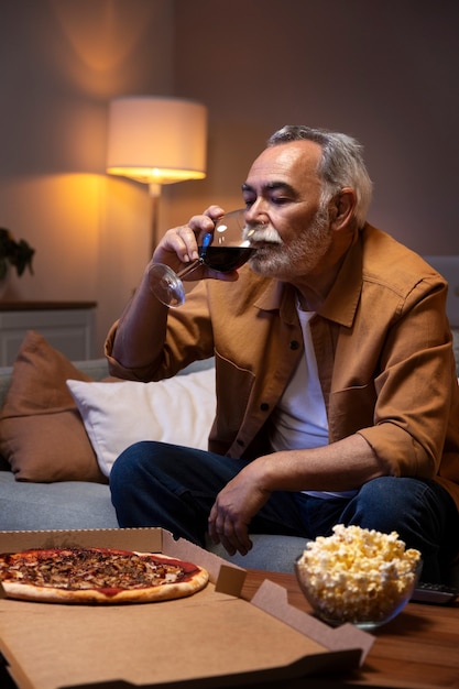 Mann, der eine Pizza und Wein genießt, während er allein zu Hause ist