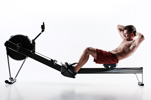 Mann, der eine Pressmaschine in einem Fitness-Club verwendet.