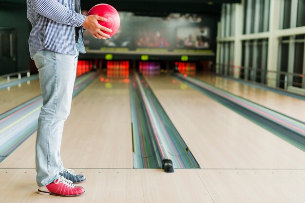 Mann, der eine rote Bowlingkugel hält