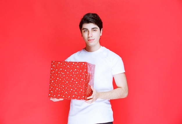 Mann, der eine rote große Geschenkbox hält