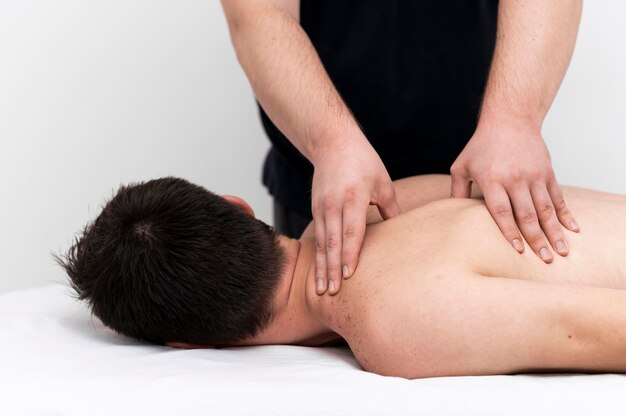 Mann, der eine Rückenmassage durch Physiotherapeuten gegeben wird