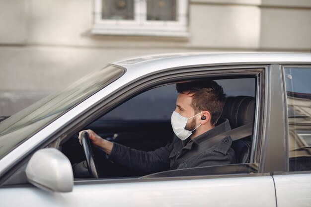 Mann, der eine Schutzmaske sitzt, die in einem Auto sitzt