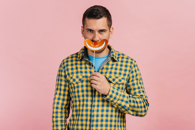 Mann, der einen gefälschten Mund mit rosa Hintergrund hält