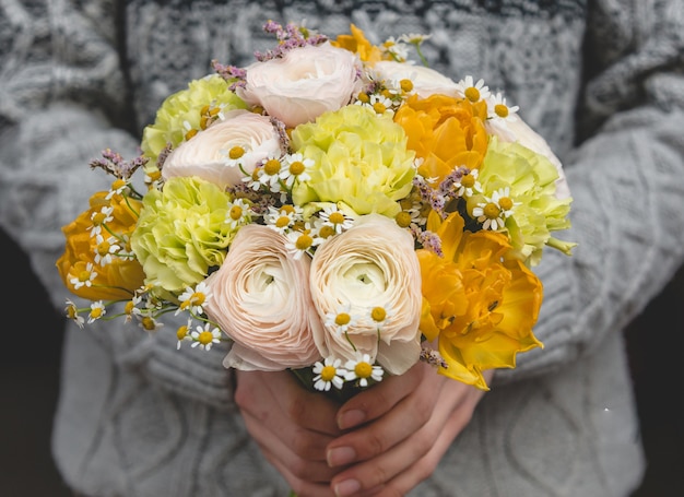 Mann, der einen gelben getonten Blumenblumenstrauß im Winter anbietet