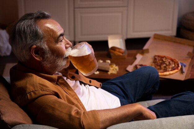 Mann, der etwas Bier genießt, während er allein zu Hause ist