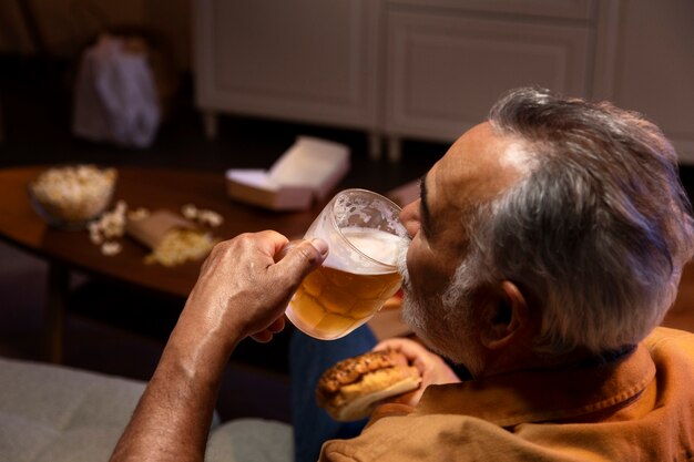 Mann, der etwas Bier genießt, während er allein zu Hause ist