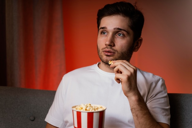 Kostenloses Foto mann, der fernsieht und popcorn isst