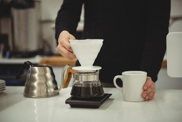 Mann, der Filtertrichter und Kaffeetasse hält