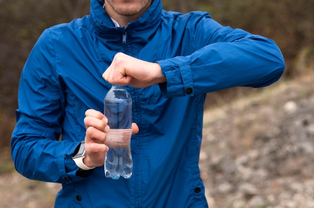 Kostenloses Foto mann, der flasche wasser in der natur hält