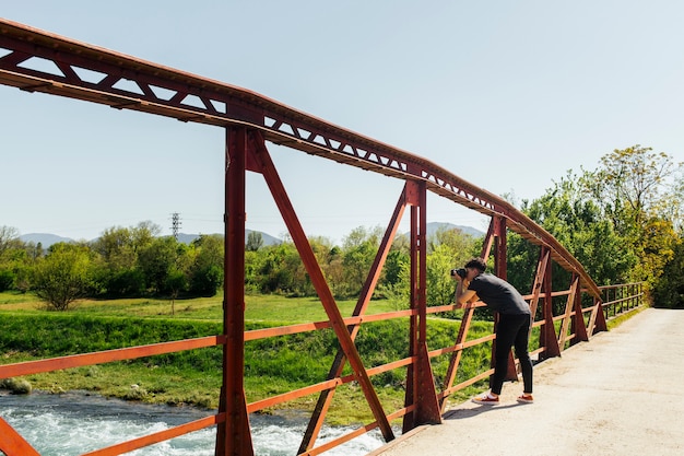 Mann, der foto des flüssigen wassers von der brücke macht