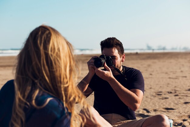 Kostenloses Foto mann, der fotos der freundin auf strand macht