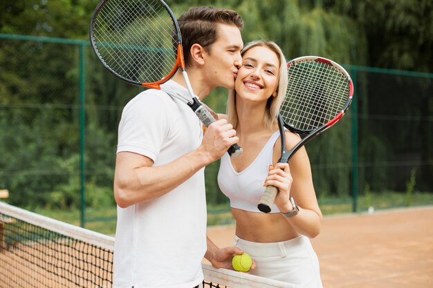 Mann, der Frau auf dem Tennisplatz küsst