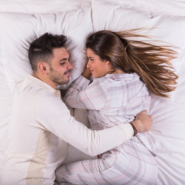 Mann, der Frau im Bett umarmt