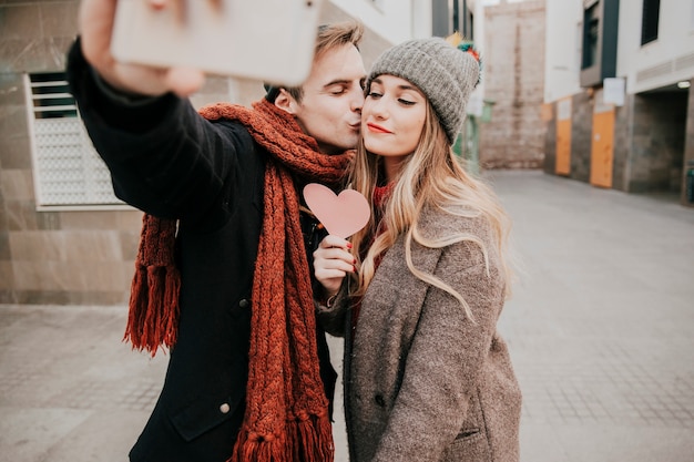 Mann, der Frau küsst und selfie nimmt