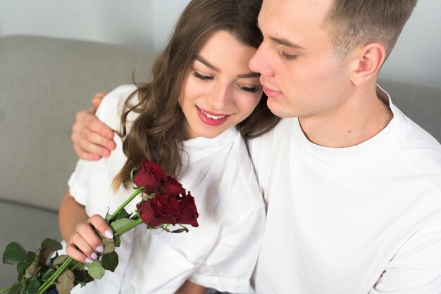 Mann, der Frau mit Blumen auf Couch umarmt