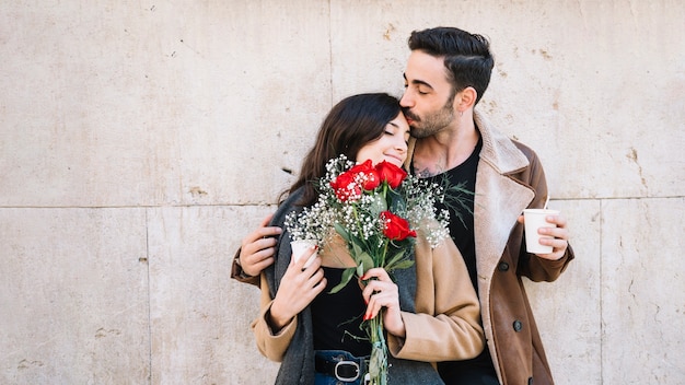 Mann, der Frau mit Blumenstrauß küsst