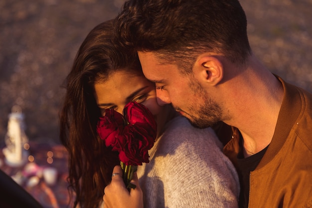 Mann, der Frau mit roten Rosen umarmt