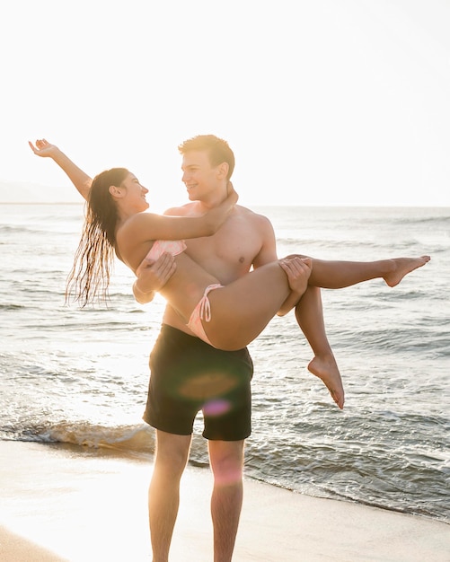 Mann, der Freundin am Strand hält