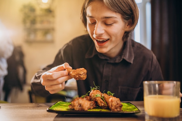 Mann, der gebratenes Huhn mit Soße in einem Café isst