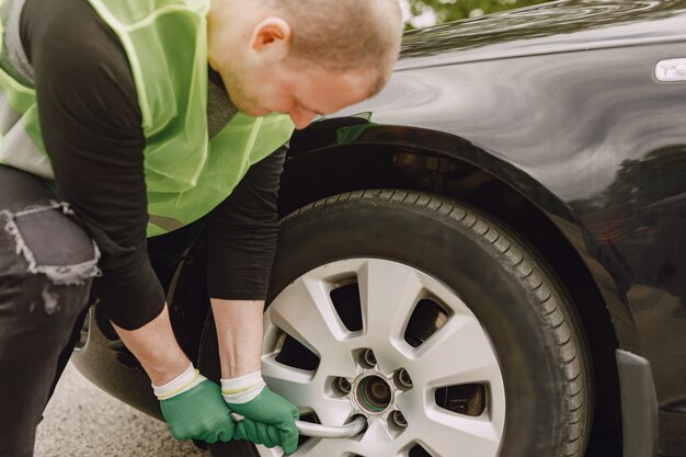 Mann, der gebrochenes Rad am Auto wechselt