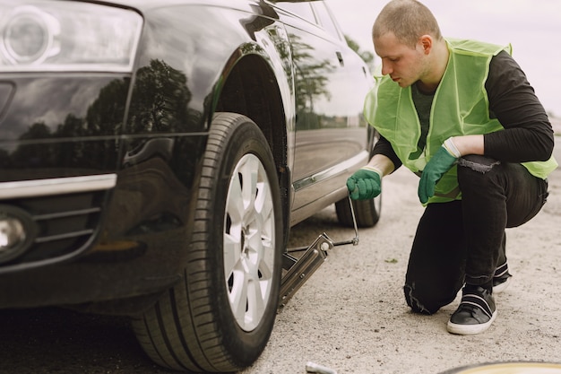 Kostenloses Foto mann, der gebrochenes rad am auto wechselt