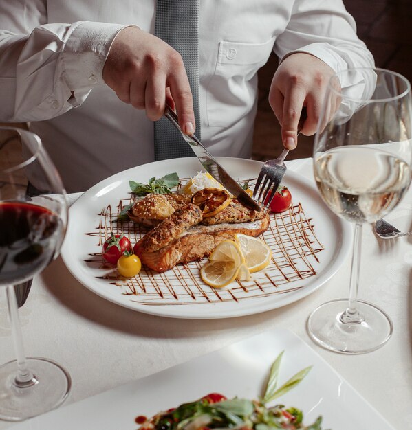 Mann, der gegrillten Lachs mit Reis, Lula Kebab, Läusen, Tomaten, Wein schneidet