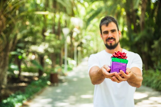 Mann, der Geschenk im Park hält