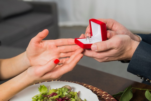 Mann, der Geschenkbox Frau bei Tisch darstellt