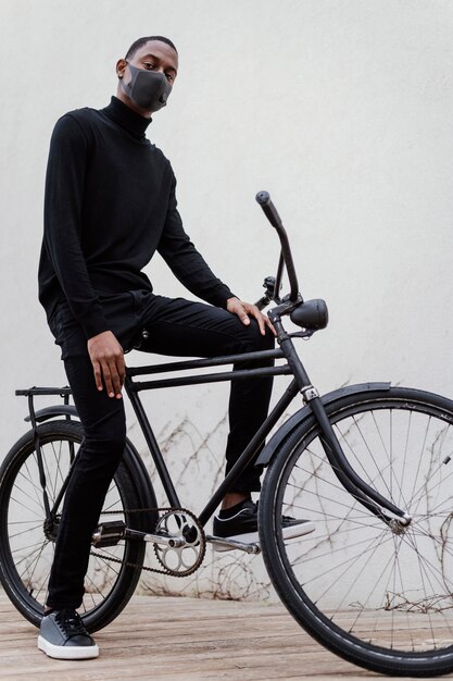 Mann, der Gesichtsmaske trägt und sein Fahrrad reitet