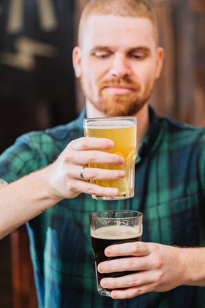 Mann, der Gläser Rum und Bier hält