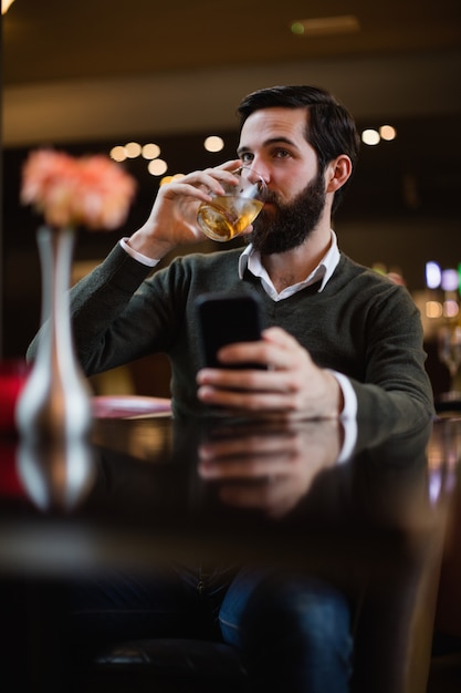 Mann, der Handy hält und etwas trinkt