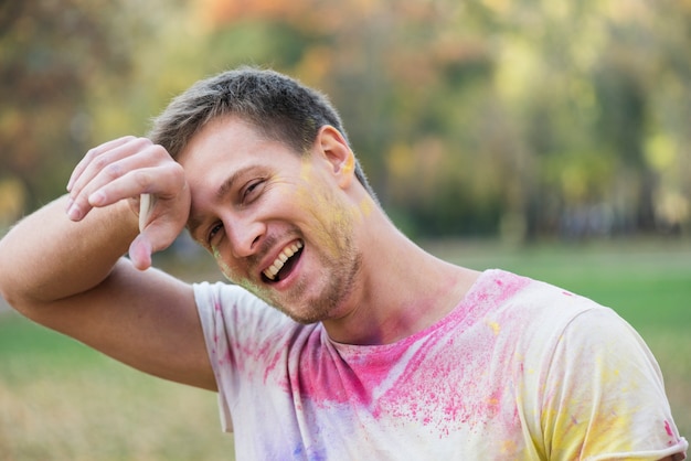 Kostenloses Foto mann, der holi mit farbigem t-shirt genießt