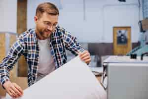 Kostenloses Foto mann, der im druckhaus mit papier und farben arbeitet