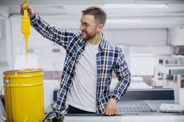 Mann, der im Druckhaus mit Papier und Farben arbeitet