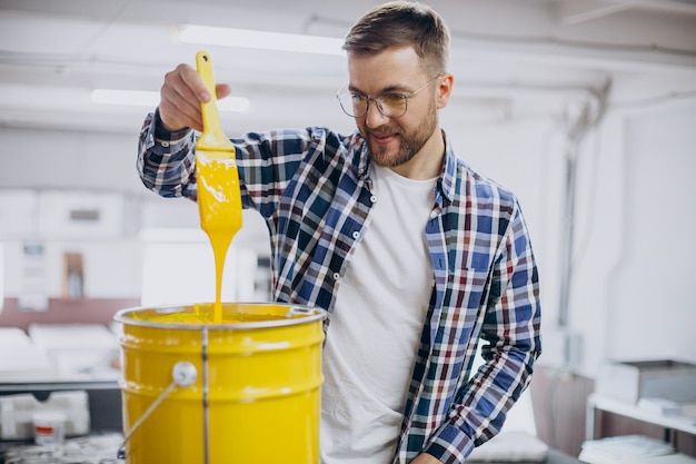 Kostenloses Foto mann, der im druckhaus mit papier und farben arbeitet