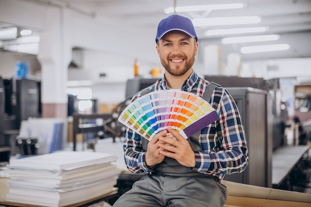 Mann, der im Druckhaus mit Papier und Farben arbeitet