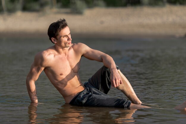 Mann, der im Wasser am Strand sitzt