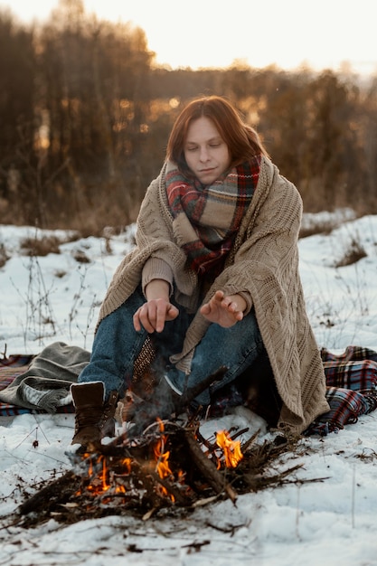 Mann, der im Winter neben einem Lagerfeuer aufwärmt