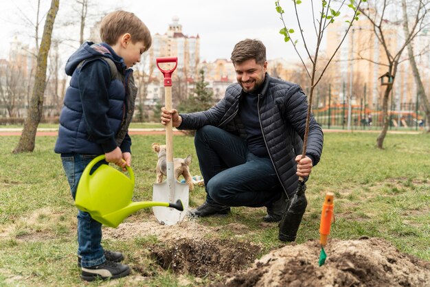 Mann, der in den Boden einen kleinen Baum plattiert