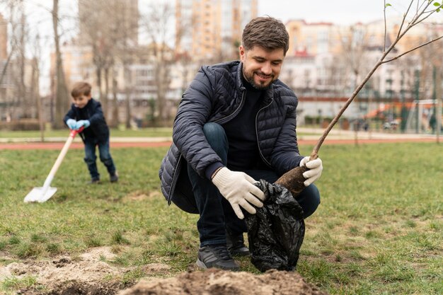 Mann, der in den Boden einen kleinen Baum plattiert