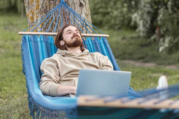 Mann, der in der Natur beim Sitzen in der Hängematte entspannt