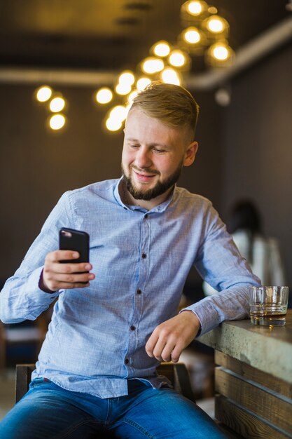 Mann, der in der Stange verwendet Handy sitzt