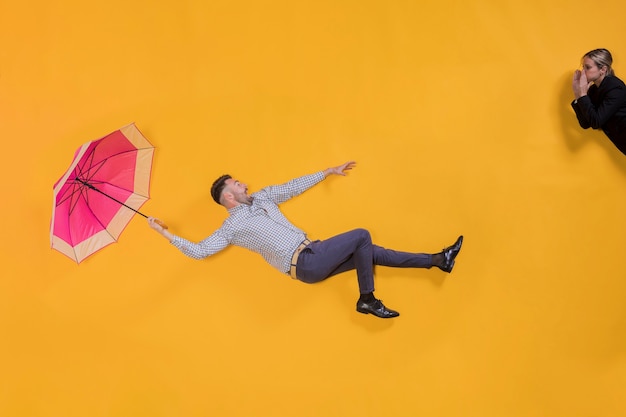 Mann, der in die Luft mit einem Regenschirm schwimmt