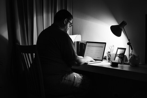 Mann, der in einem dunklen Innenministerium mit einem Laptop arbeitet