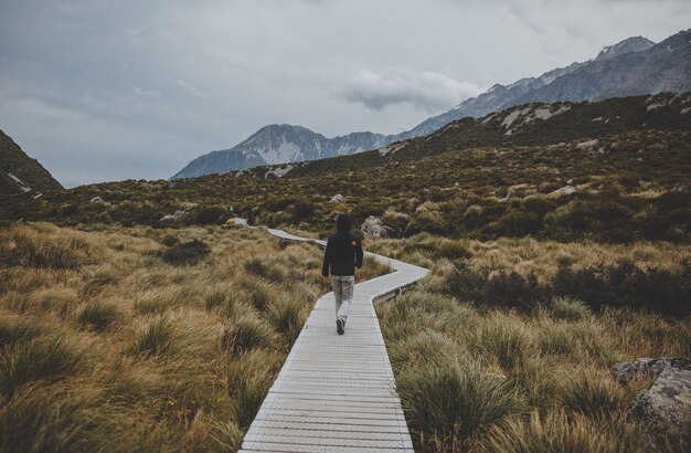 Mann, der in Hooker Valley mit Blick auf Mount Cook in Neuseeland geht