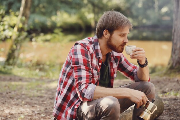 Mann, der Kaffee im Wald trinkt