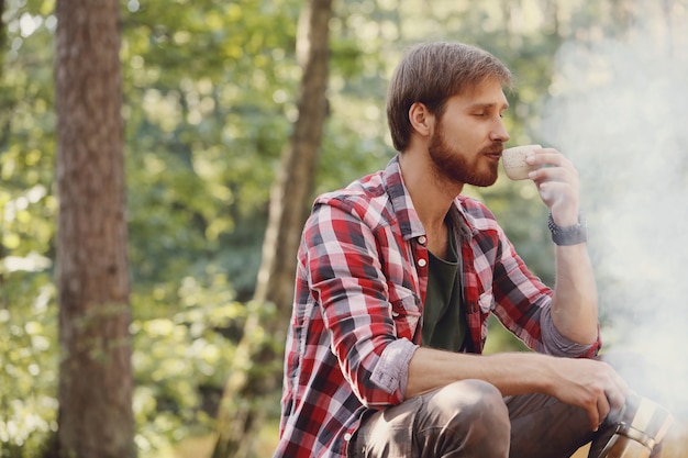 Mann, der Kaffee im Wald trinkt