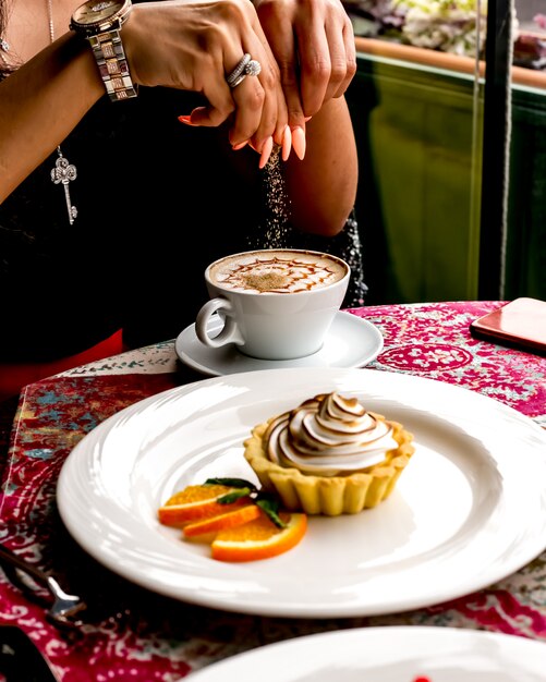 Mann, der Kaffee mit Wüstentörtchen mit Sahne und orange Seitenansicht hat