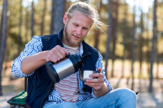 Kostenloses Foto mann, der kaffee von der thermoskanne gießt